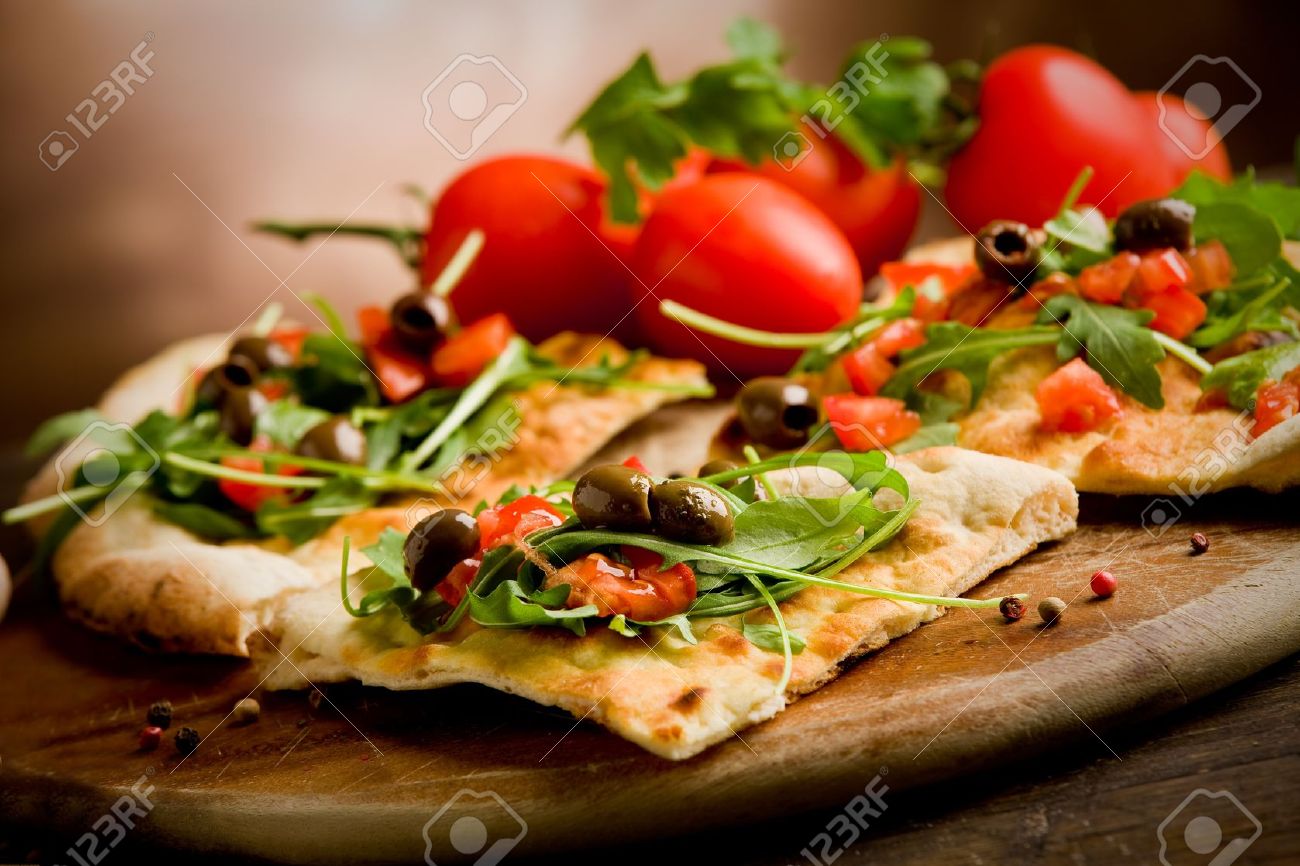 11560119-photo-of-delicious-vegetarian-pizza-with-arugula-on-wooden-table-stock-photo